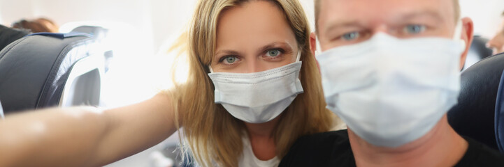 Young family couple in protective masks on the plane