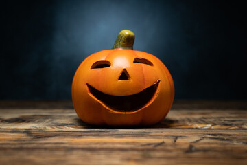 Small ceramic Halloween pumpkin. Jack-o'-lantern decoration at night. Decorative spooky carved Jack Lantern figurine head.