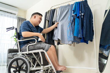 Asian young man with autism choosing clothes on closet rack at home. 