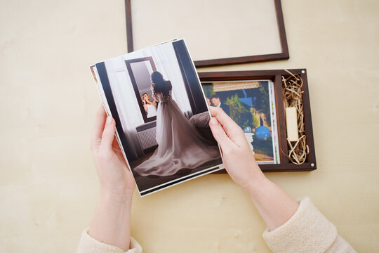 printed wedding photos in the hands and in a wooden box with a flash drive. 