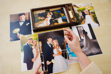 Fototapeta na wymiar printed wedding photos in the hands and in a wooden box with a flash drive. 
