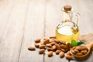 Almond oil with almond nuts on wooden table.