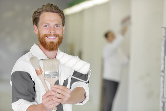 men with brush and roller smiling at camera