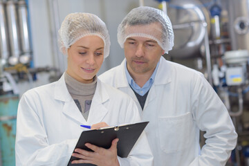 man and woman wearing hair nets making notes on clipboard