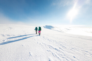Fototapeta na wymiar two girls in snowshoes walk in the snow. hiking in the mountains in winter.
