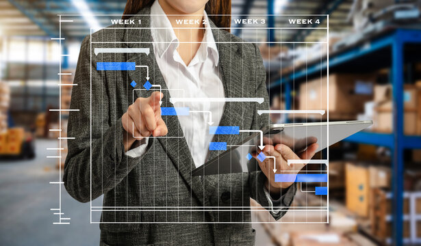  Storage worker in uniform Wearing Hard Hat Checks Stock and Inventory and Gantt chart scheduling diagram.business .with Digital Tablet Computer in the Warehouse - Powered by Adobe