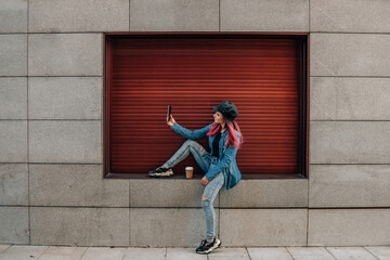 girl with mobile phone sitting on the window