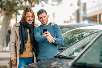 couple with mobile phone looking at cars to buy, buy car