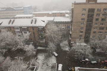 Houses and tree branches during heavy snowfall in the city in early autumn, weather and weather phenomena, environment