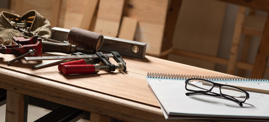 carpenter's tools and notebook on furniture
