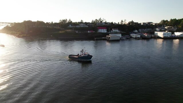 360 drone panorama of fishing ship entering harbor at sunset.