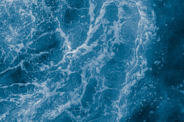 Dark blue sea surface with waves, splash and bubbles