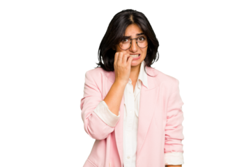 Young Indian business woman wearing a pink suit isolated biting fingernails, nervous and very anxious.