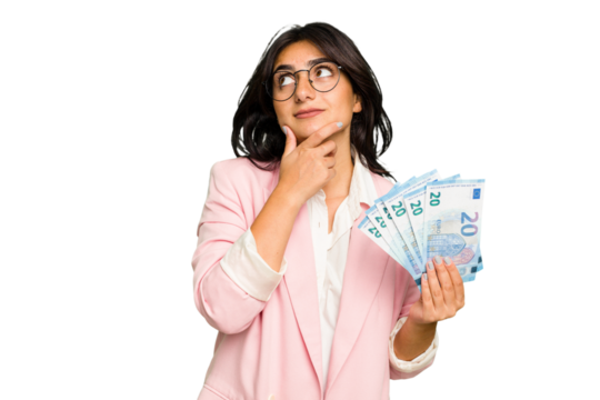 Young business Indian woman holding banknotes isolated looking sideways with doubtful and skeptical expression.