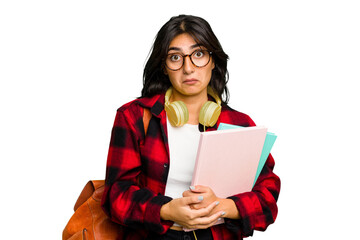 Young student Indian woman wearing headphones isolated shrugs shoulders and open eyes confused.