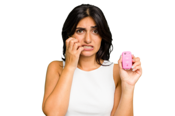 Young Indian woman holding a car keys isolated biting fingernails, nervous and very anxious.