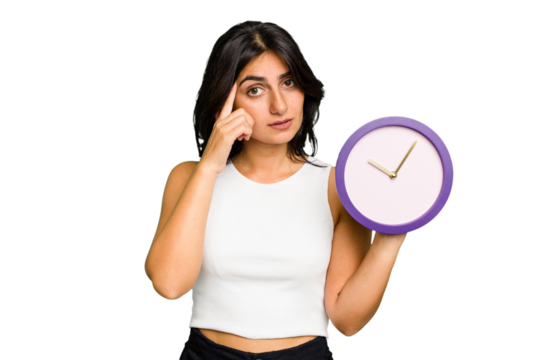 Young Indian woman holding a clock isolated pointing temple with finger, thinking, focused on a task.