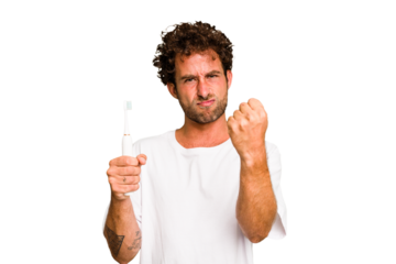 Young caucasian man holding an electric toothbrush isolated showing fist to camera, aggressive facial expression.
