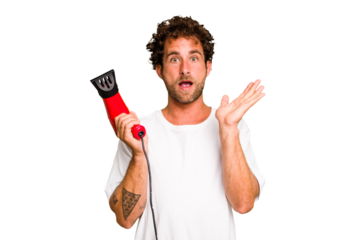 Young caucasian man holding an hairdryer isolated surprised and shocked.