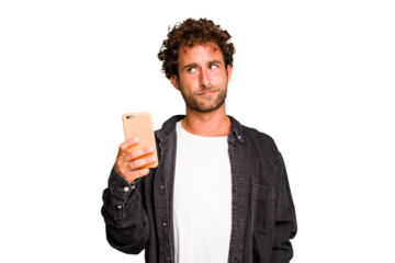 Young caucasian man using mobile phone isolated confused, feels doubtful and unsure.