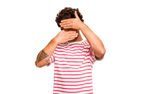 Young caucasian curly hair man isolated Young caucasian man with curly hair isolated blink at the camera through fingers, embarrassed covering face.
