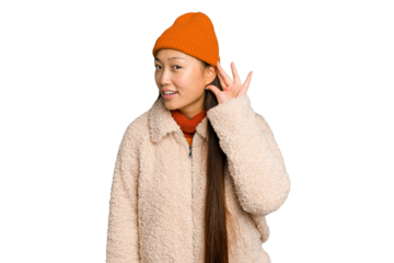 Young asian woman wearing winter clothes isolated on green chroma background trying to listening a gossip.