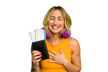 Young caucasian woman with inflatable travel pillow holding passport isolated on green chroma background laughs out loudly keeping hand on chest.