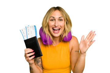 Young caucasian woman with inflatable travel pillow holding passport isolated on green chroma background receiving a pleasant surprise, excited and raising hands.