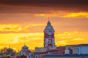 Old tower clock of railway station of Varna city, Bulgaria and flying birds at sunset - Powered by Adobe