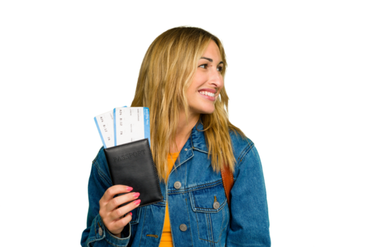 Young caucasian woman holding a passport isolated on green chroma background looks aside smiling, cheerful and pleasant.