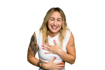 Young caucasian woman isolated on green chroma background laughs happily and has fun keeping hands on stomach.