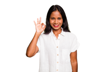 Young Indian woman isolated winks an eye and holds an okay gesture with hand.