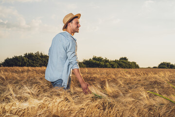 Happy farmer is standing in his growing barley field.	
