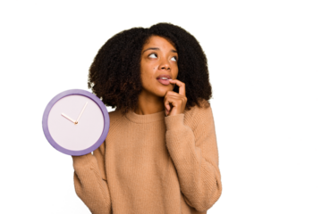 Young African American holding a clock isolated relaxed thinking about something looking at a copy space.