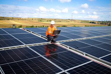 Professional worker using his laptop computer and checking voltage or energy production of solar...