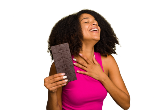 Young African American woman holding a chocolate bar isolated laughs out loudly keeping hand on chest. - Powered by Adobe