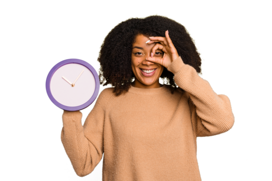 Young African American holding a clock isolated excited keeping ok gesture on eye.