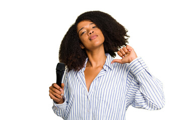 Young African American singer woman holding a microphone isolated feels proud and self confident,...