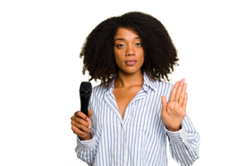 Young African American singer woman holding a microphone isolated standing with outstretched hand showing stop sign, preventing you.