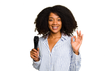 Young African American singer woman holding a microphone isolated cheerful and confident showing ok gesture.