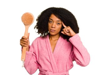 Young African American woman holding a shower brush isolated pointing temple with finger, thinking, focused on a task.