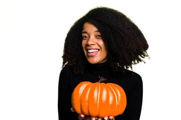 Young African American woman holding a pumpkin for halloween day isolated