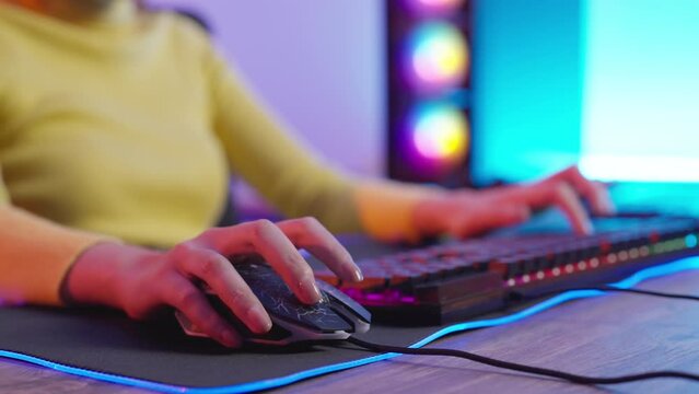 Hands of the female gamer playing in the video game using  with RGB keyboard. Close Up Hands on Keyboard.