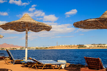 Sun umbrellas and chaise lounges on tropical beach. Concept of rest, relaxation, holidays, resort