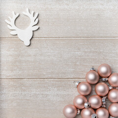 Christmas decoration, pink baubles and a reindeer on a wooden background. Top view, copy space	