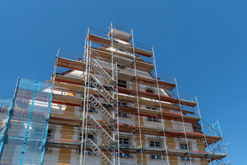 Baugerüst mit Leitern an einem großen alten Haus mit neu gestrichener Fassade