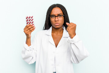 Young African American pharmacist woman isolated on blue background showing fist to camera,...