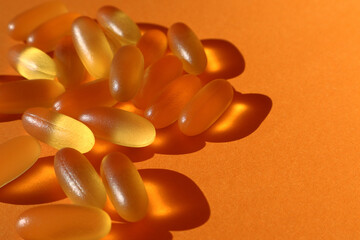 Dietary supplementation. omega-3 fish fat oil capsules. Orange background.