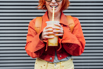 Fruity sugar flavored tapioca pearl bubble tea with straw is drinking by smiling hipster fashion...