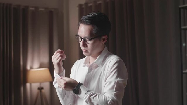 Asian Man In White Classic Shirt Putting On Cufflinks. Dressing For Celebration Event, Business Meeting Or Wedding
